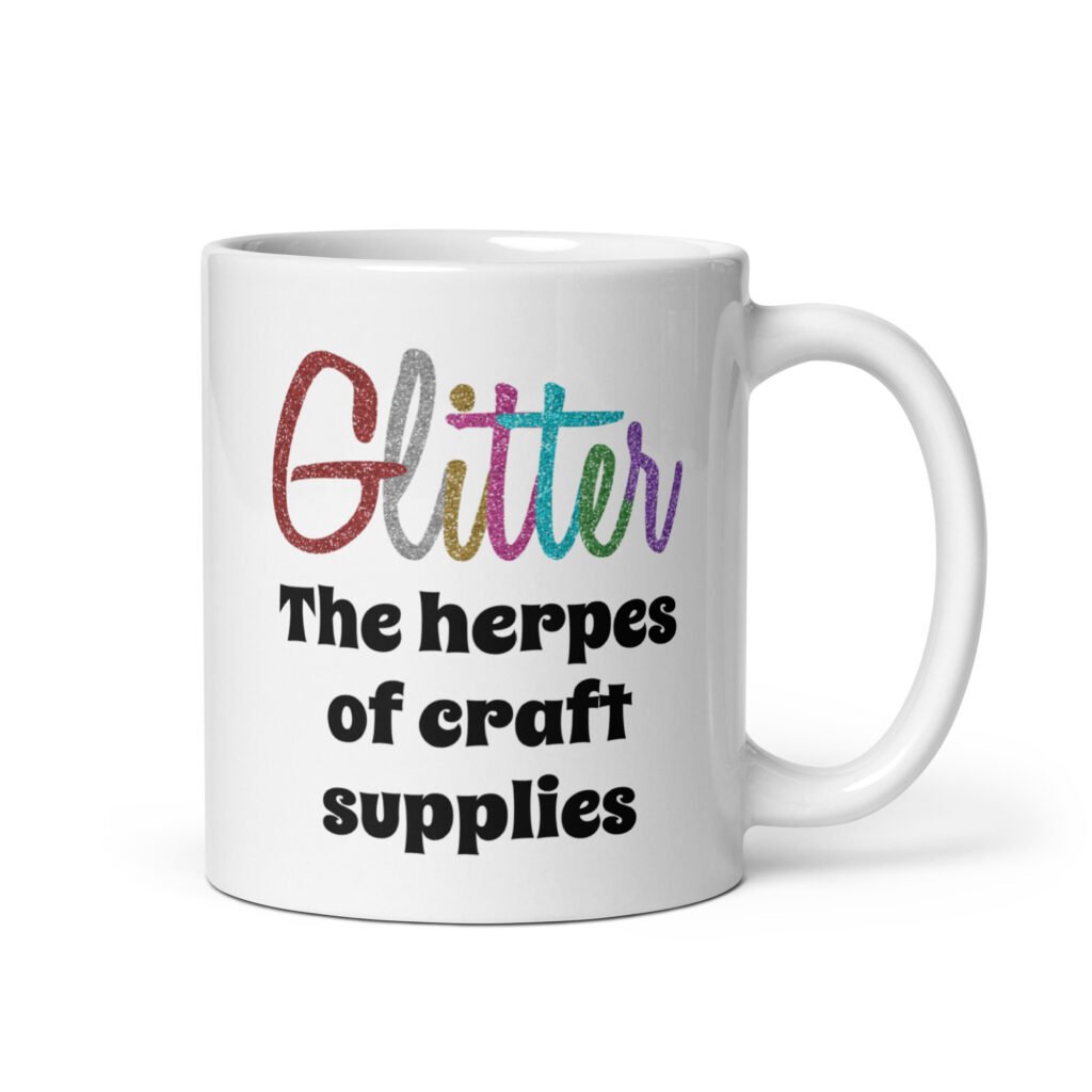 White ceramic coffee mug with the text 'Glitter the herpes of craft supplies' printed on both sides. The word Glitter is printed in multi colored font that looks like glitter.