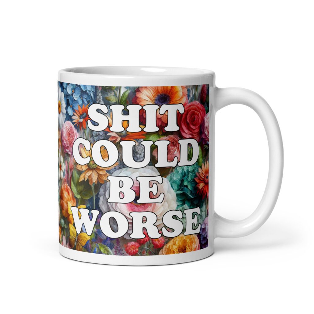 White ceramic mug floral background and the text 'Shit could be worse' printed on both sides.