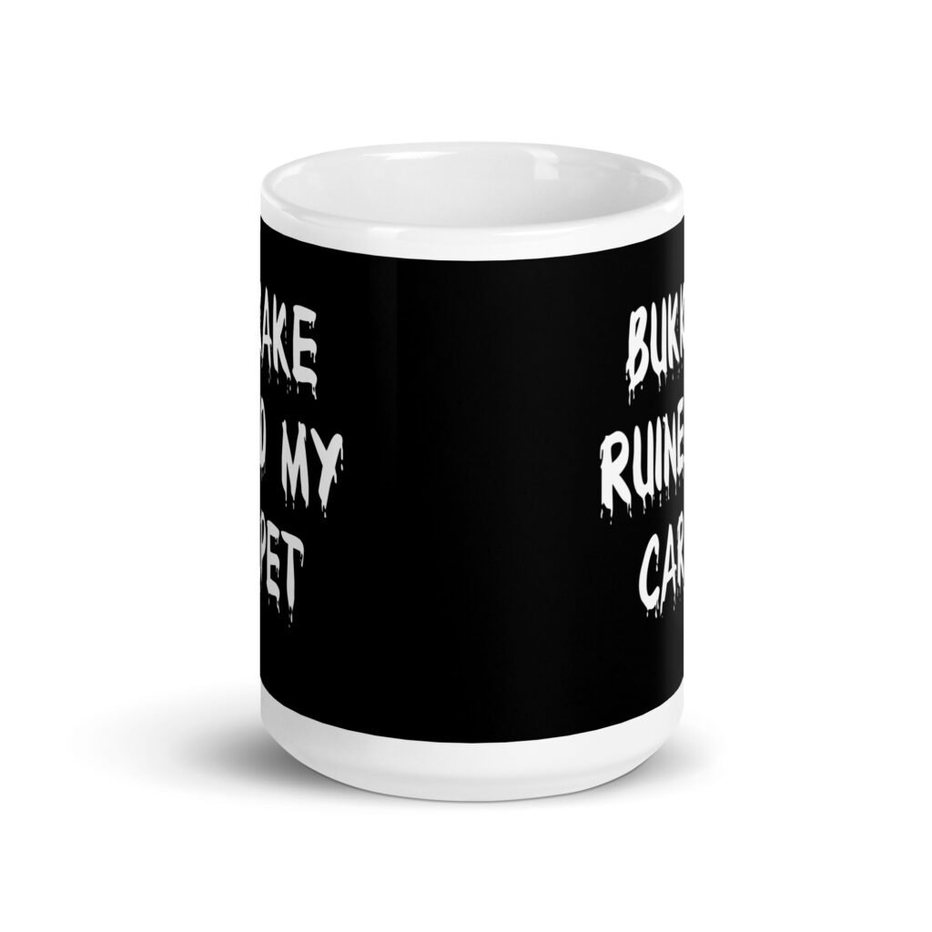 White and black ceramic coffee mug with the text 'Bukkake ruined my carpet' printed in drippy font on both sides.