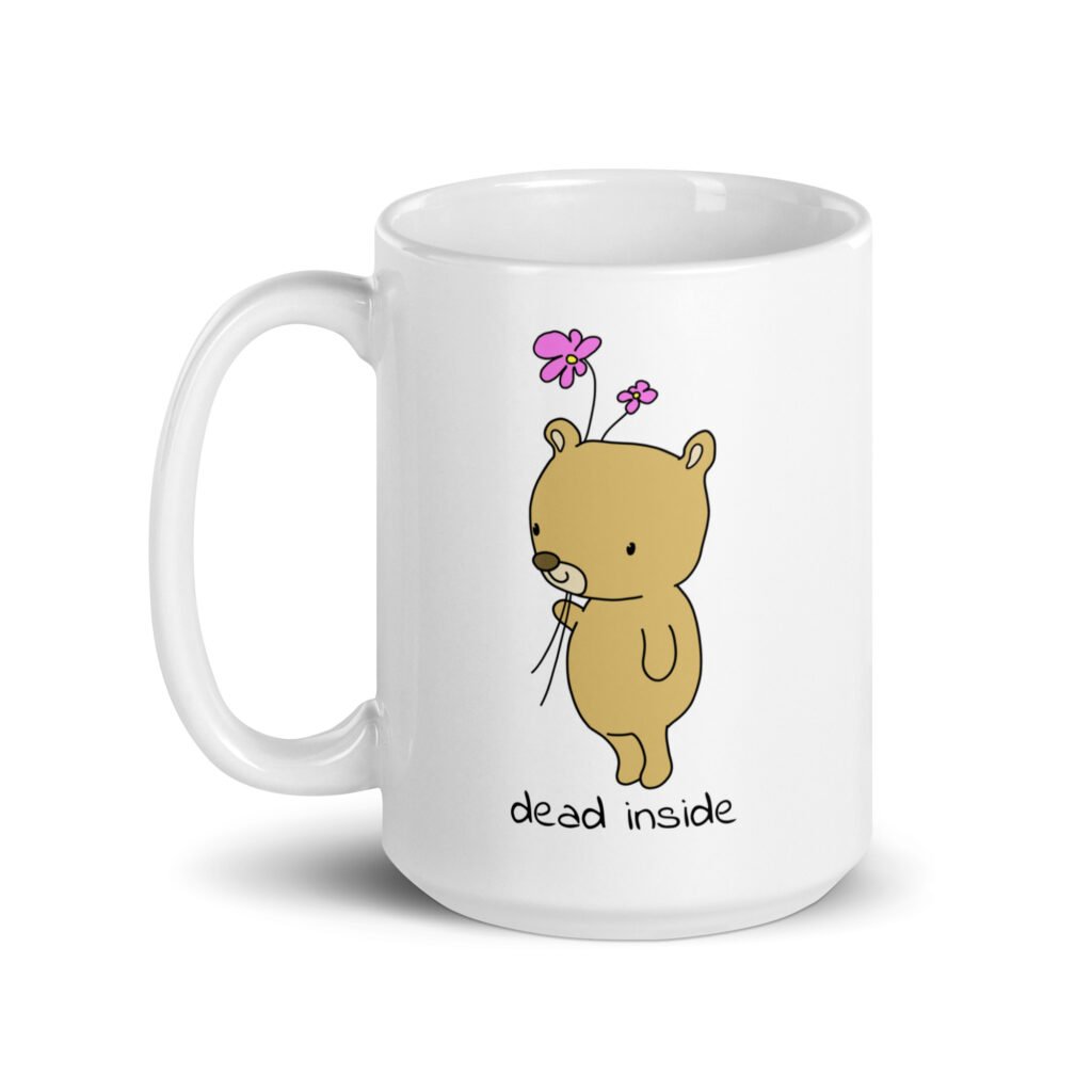 White ceramic coffee mug with an image of a cute bear holding 2 pink flowers. The words 'dead inside' are printed underneath the bear. The graphics are printed on both sides.