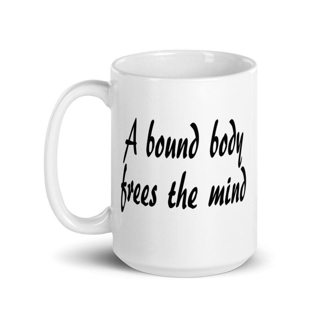 White ceramic coffee mug with the text 'A bound body frees the mind' printed on both sides.