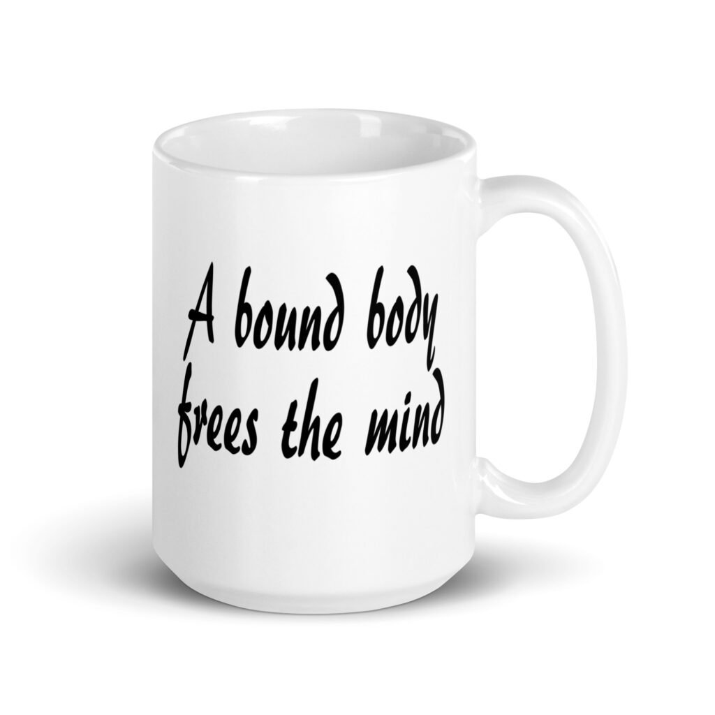 White ceramic coffee mug with the text 'A bound body frees the mind' printed on both sides.