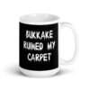 White and black ceramic coffee mug with the text 'Bukkake ruined my carpet' printed in drippy font on both sides.
