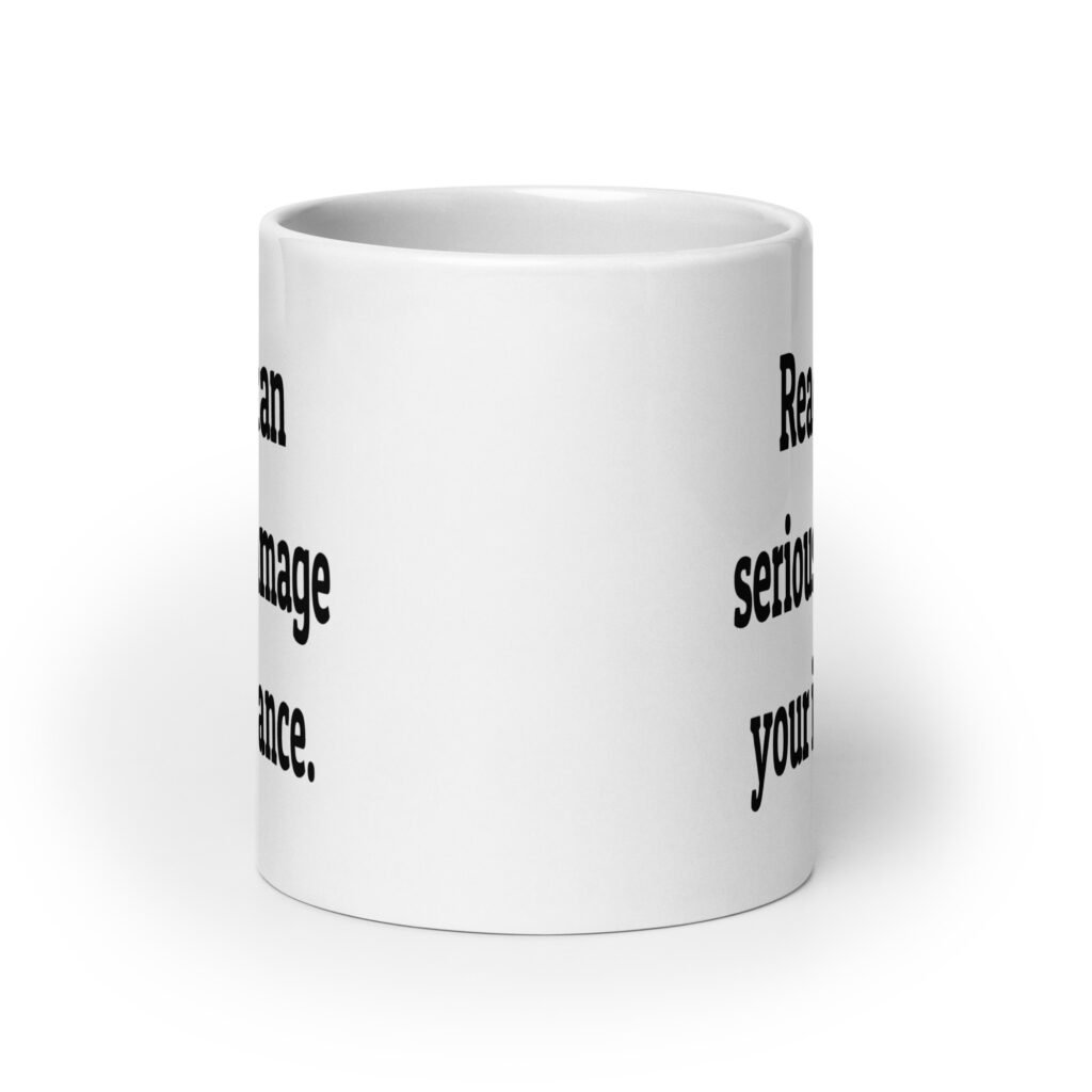 White ceramic coffee mug with the text 'Reading can seriously damage your ignorance.' printed on both sides.