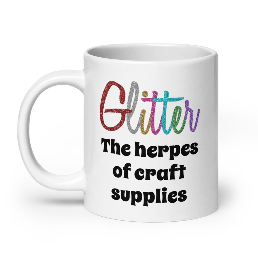 White ceramic coffee mug with the text 'Glitter the herpes of craft supplies' printed on both sides. The word Glitter is printed in multi colored font that looks like glitter.