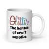 White ceramic coffee mug with the text 'Glitter the herpes of craft supplies' printed on both sides. The word Glitter is printed in multi colored font that looks like glitter.