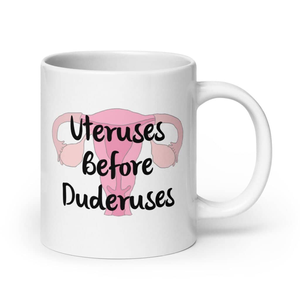 White ceramic mug with image of a uterus and the text 'Uteruses before duderuses' printed on both sides.