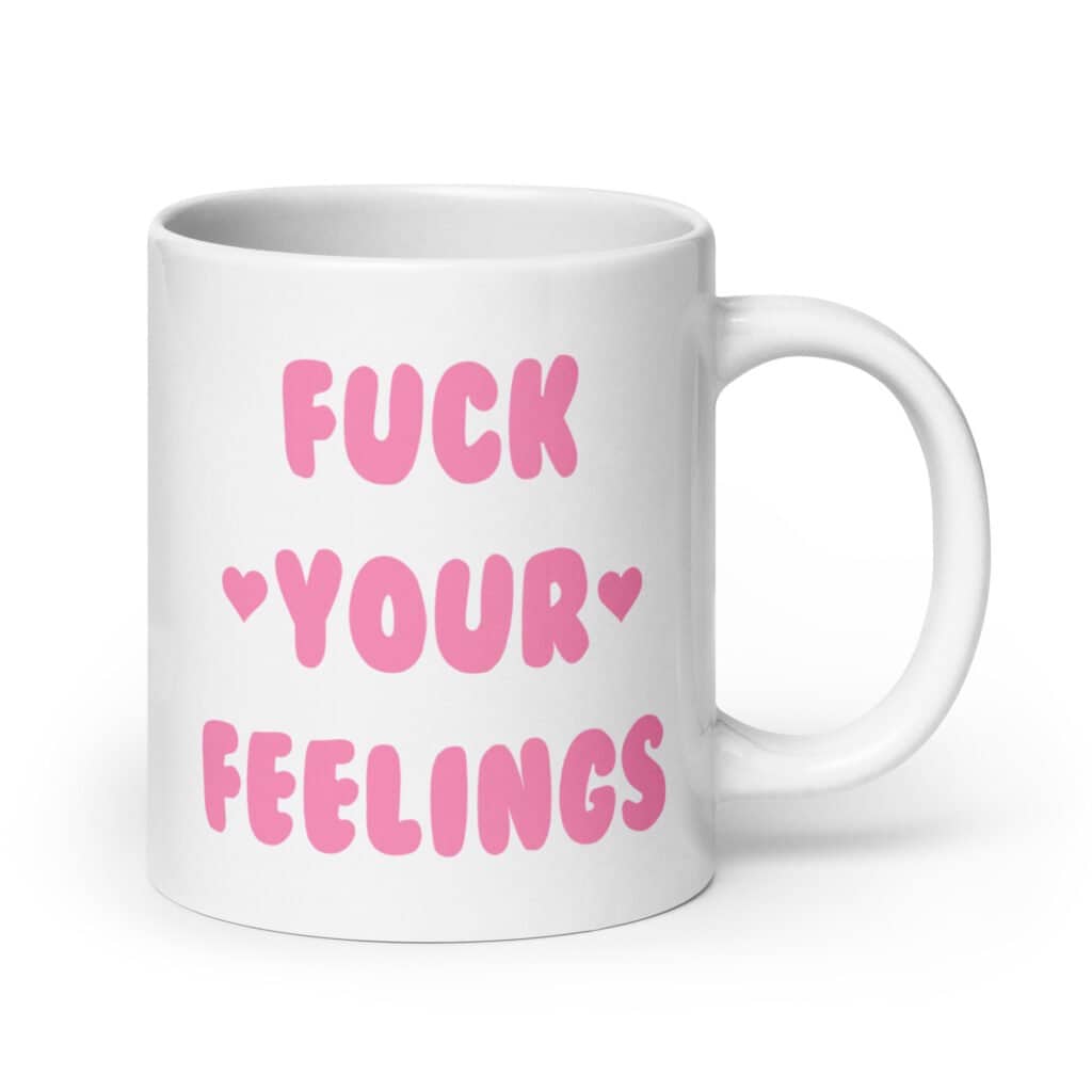 White ceramic coffee mug with the text 'Fuck your feelings' printed on both sides in pink. There are cute pink hearts next to the words.