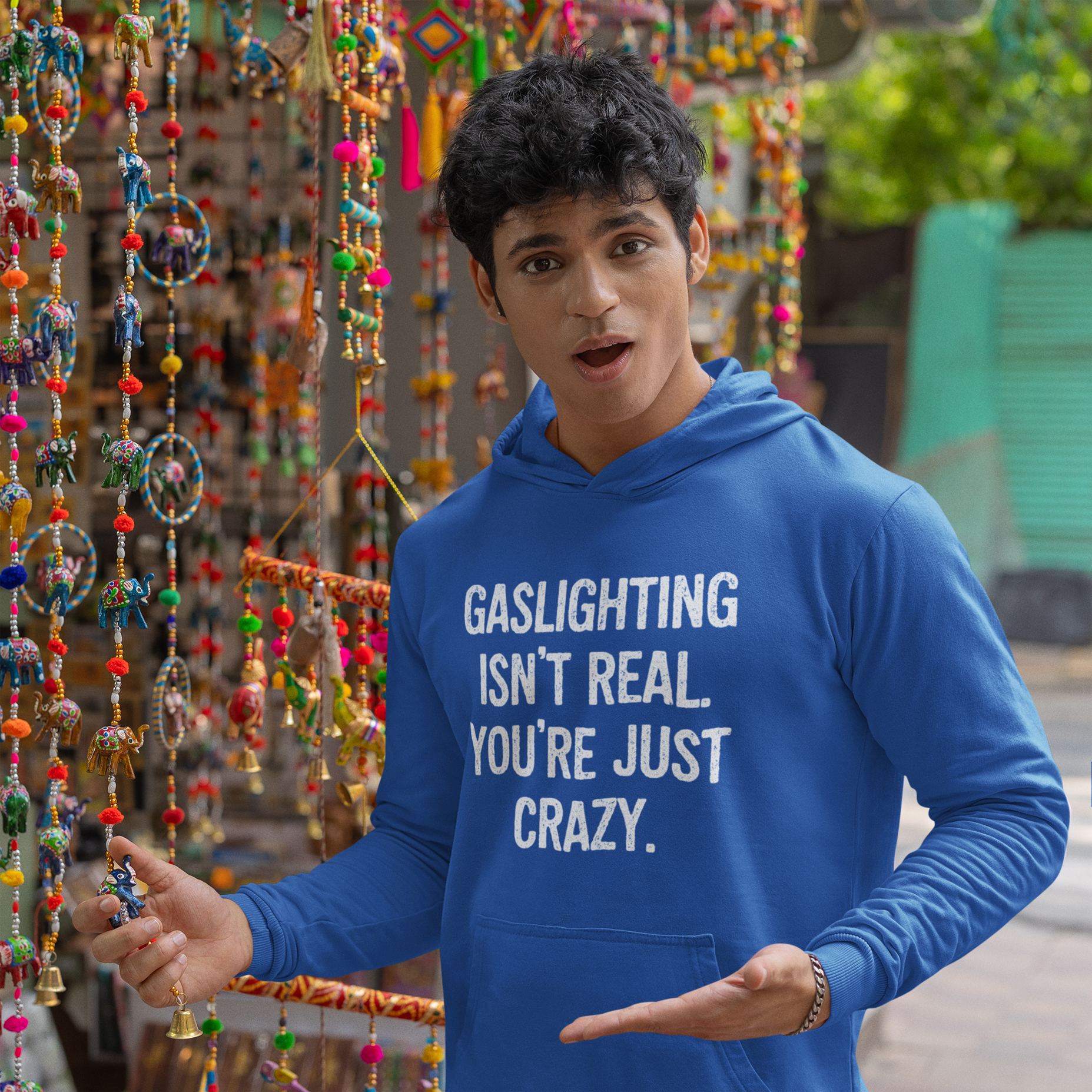 gaslighting isnt real hoodie mockup on man Man wearing a royal blue hoodie sweatshirt with the text 'Gaslighting isn't real. You're just crazy.' printed on the front in bold distressed font.