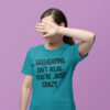 Woman wearing a tropical blue t-shirt with the text 'Gaslighting isn't real. You're just crazy.' printed on the front in bold distressed font.