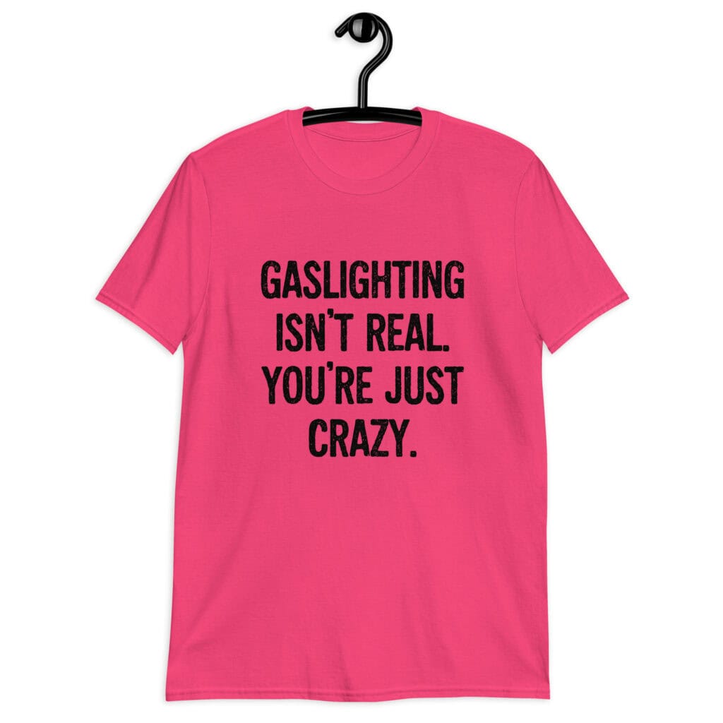 Heliconia pink t-shirt with the text 'Gaslighting isn't real. You're just crazy.' printed on the front in bold distressed font.
