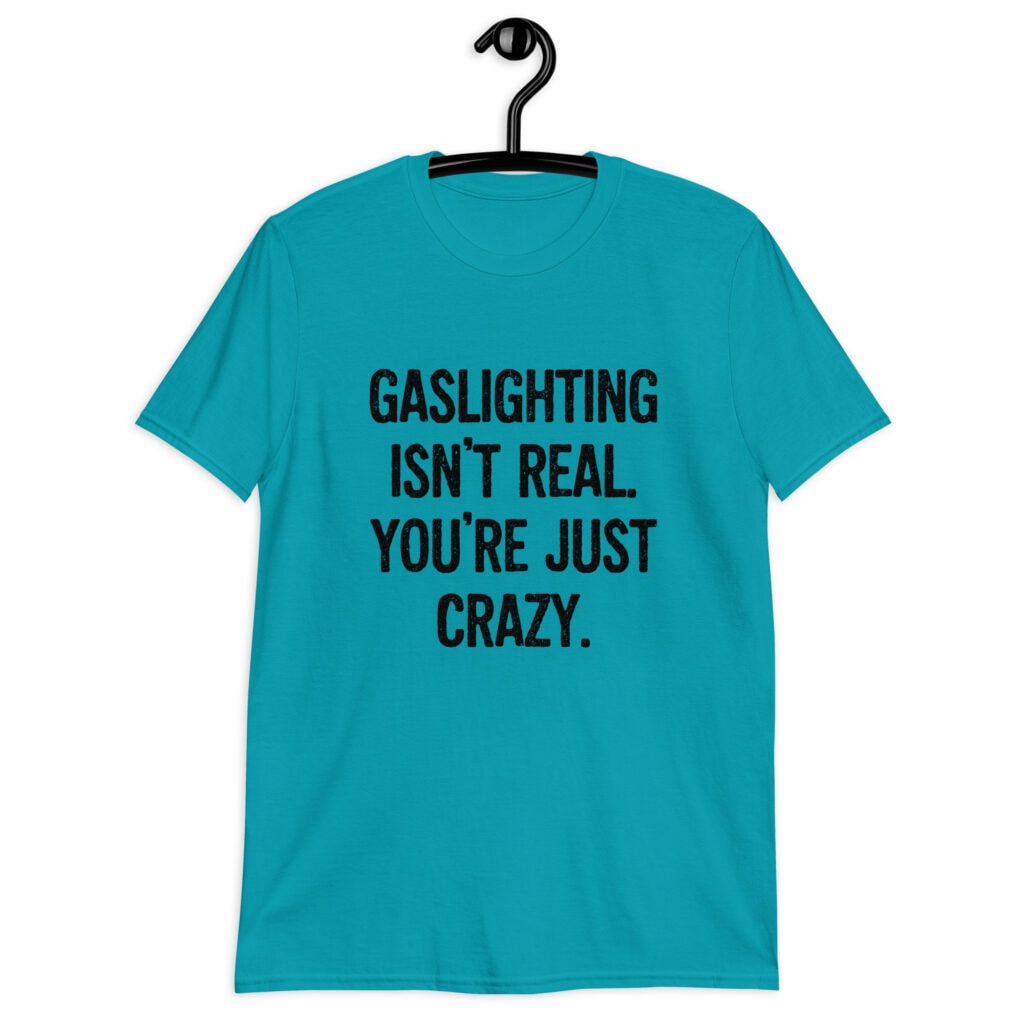 Tropical blue t-shirt with the text 'Gaslighting isn't real. You're just crazy.' printed on the front in bold distressed font.