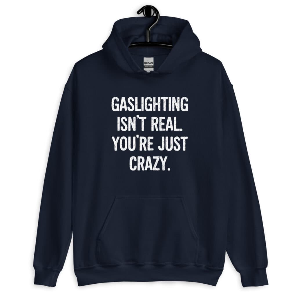 Navy blue hoodie sweatshirt with the text 'Gaslighting isn't real. You're just crazy.' printed on the front in bold distressed font.