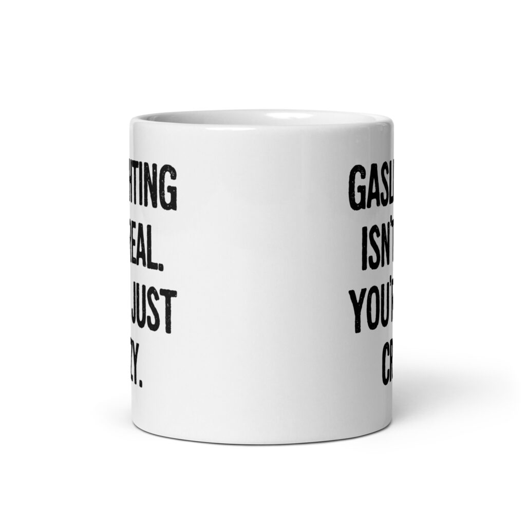 White ceramic mug with the text 'Gaslighting isn't real. You're just crazy.' printed on both sides in bold distressed font.