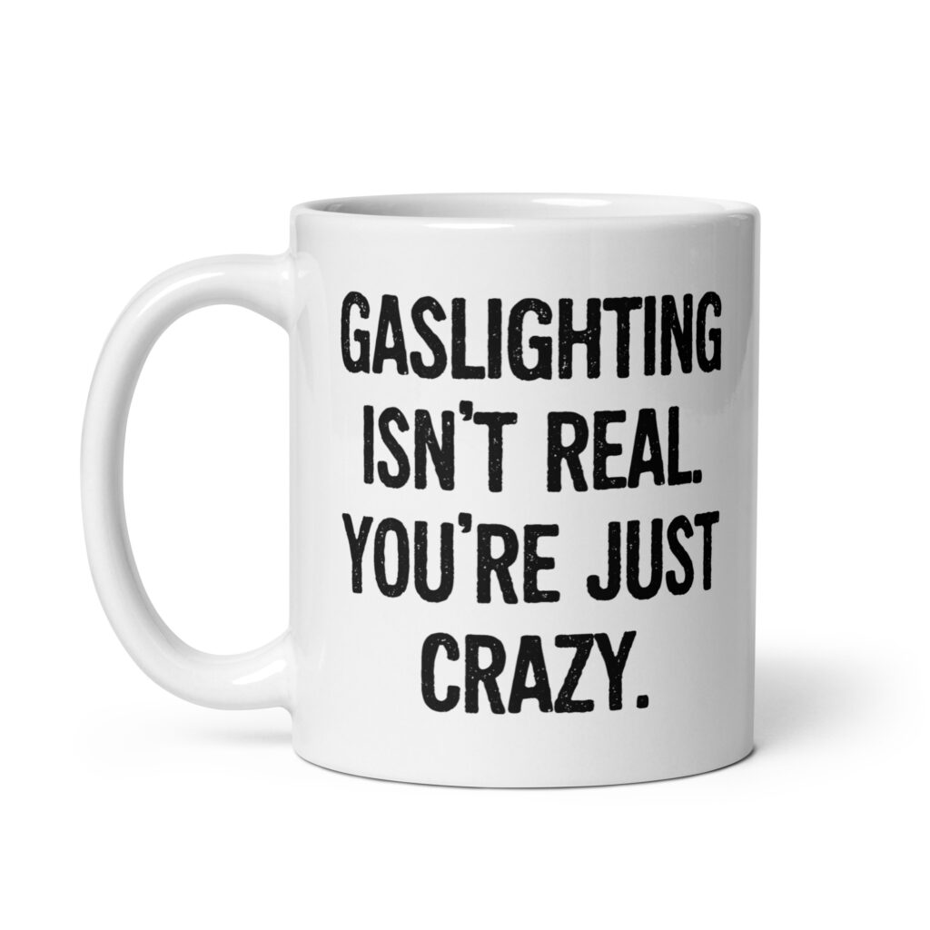 White ceramic mug with the text 'Gaslighting isn't real. You're just crazy.' printed on both sides in bold distressed font.