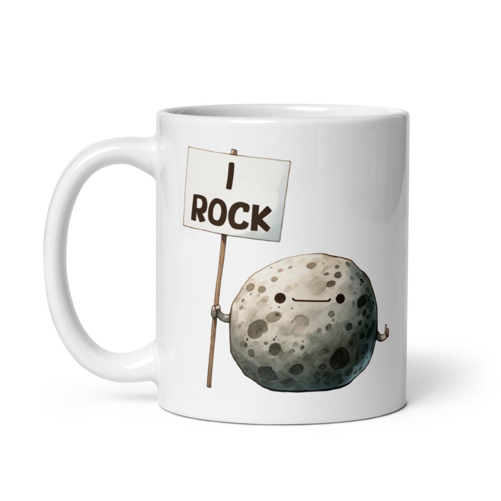 White ceramic mug that has an image of a grey rock that is holding a sign. The sign says 'I Rock.' The image is printed on both sides of the mug.