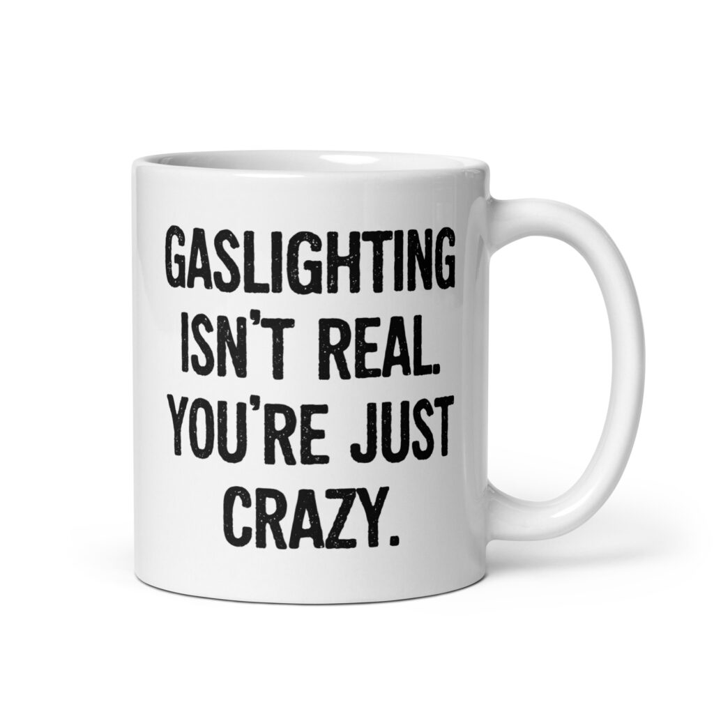 White ceramic mug with the text 'Gaslighting isn't real. You're just crazy.' printed on both sides in bold distressed font.