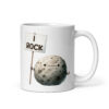White ceramic mug that has an image of a grey rock that is holding a sign. The sign says 'I Rock.' The image is printed on both sides of the mug.