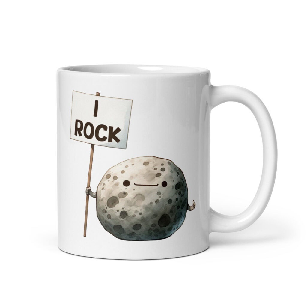 White ceramic mug that has an image of a grey rock that is holding a sign. The sign says 'I Rock.' The image is printed on both sides of the mug.