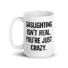 White ceramic mug with the text 'Gaslighting isn't real. You're just crazy.' printed on both sides in bold distressed font.