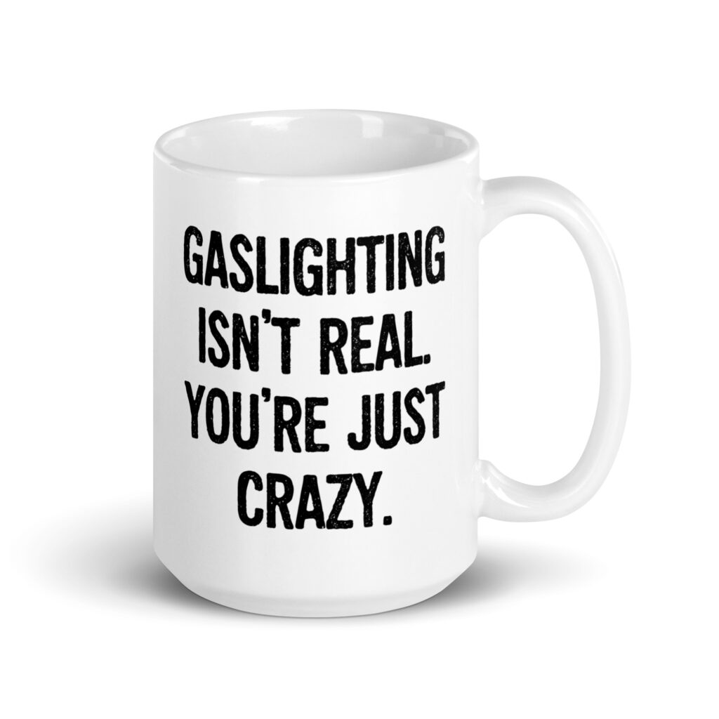 White ceramic mug with the text 'Gaslighting isn't real. You're just crazy.' printed on both sides in bold distressed font.