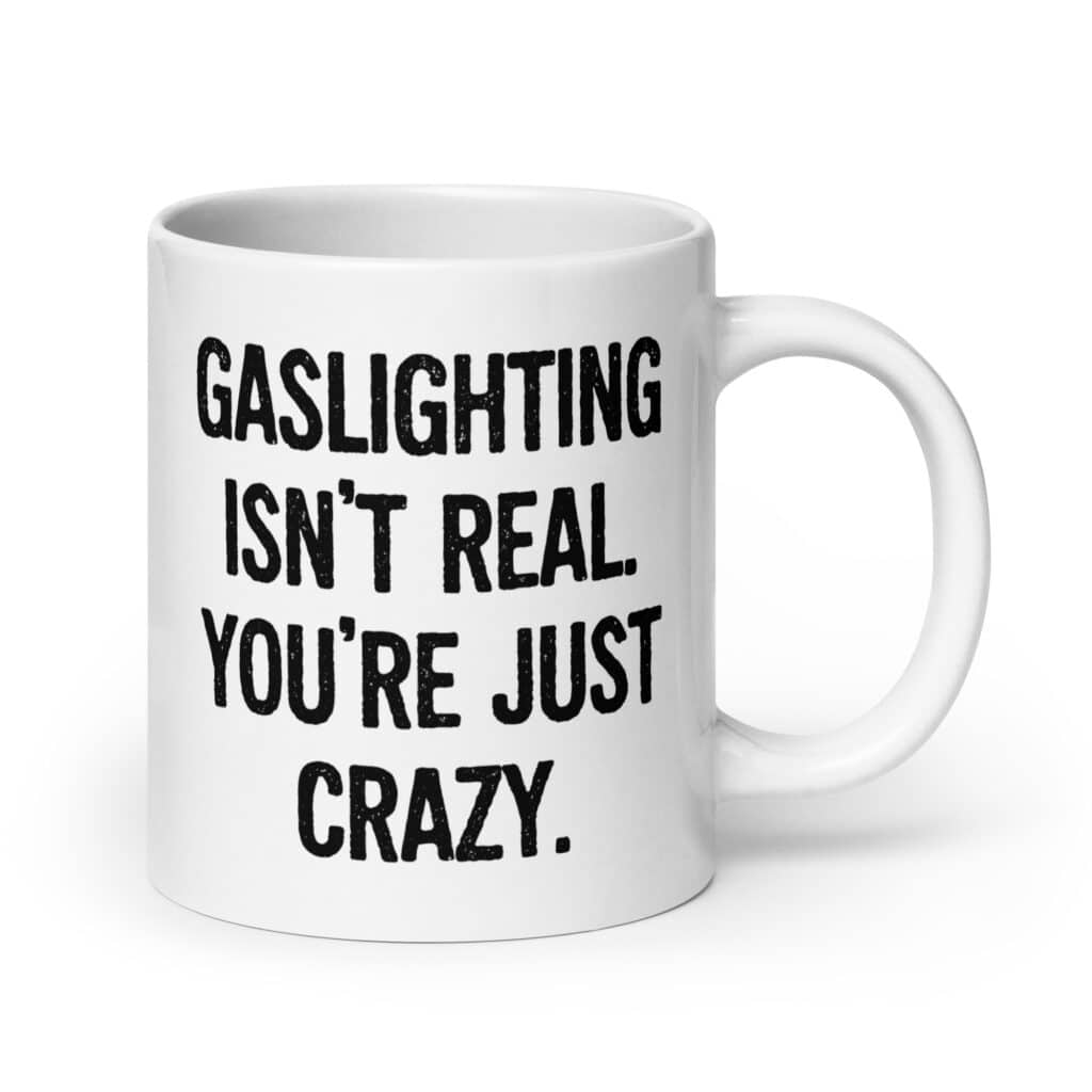 White ceramic mug with the text 'Gaslighting isn't real. You're just crazy.' printed on both sides in bold distressed font.