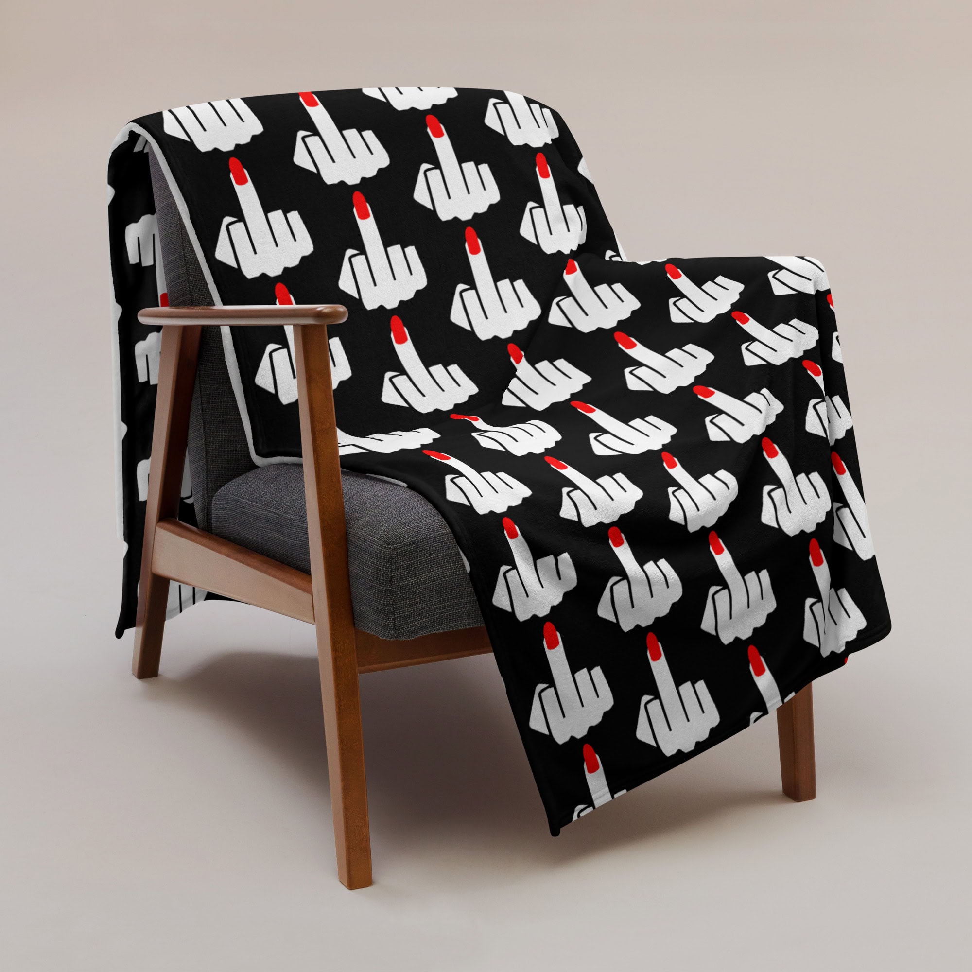 60x80 blanket with image of middle finger with long red fingernails silhouette printed all over. The blanket is black and the graphic is white and red. Shown draped over a chair