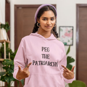 Woman wearing a light pink hoodie sweatshirt with the text 'PEG THE PATRIARCHY' printed on the front.