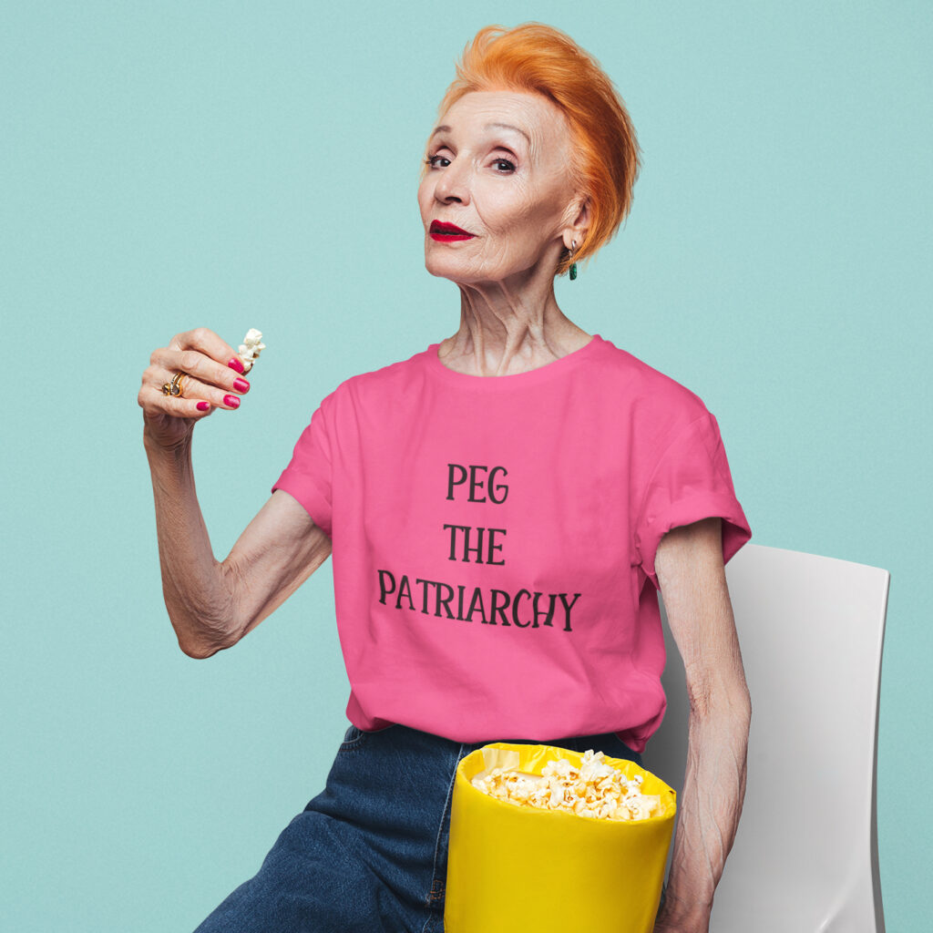 Woman wearing a heliconia pink t-shirt with the text 'PEG THE PATRIARCHY' printed on the front.