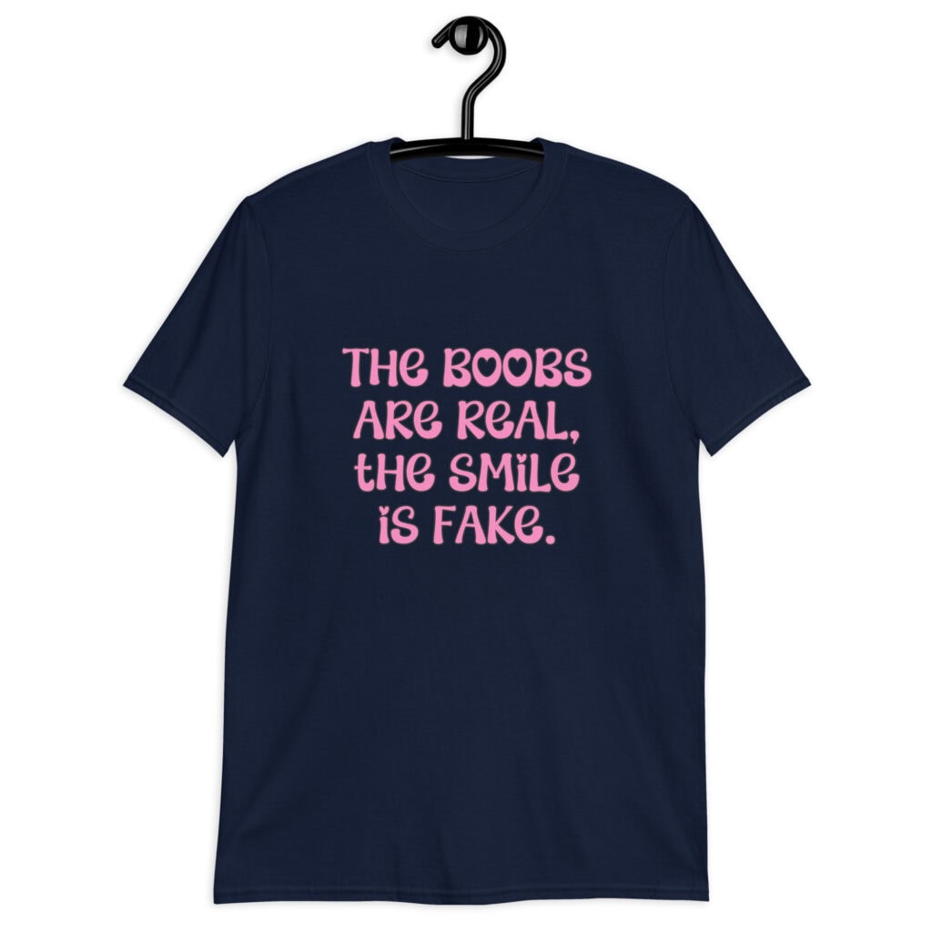 Navy blue t-shirt with the text 'The boobs are real, the smile is fake.' printed in pink on the front.