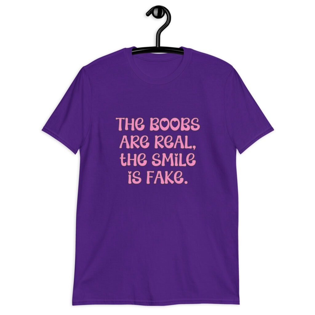 Purple t-shirt with the text 'The boobs are real, the smile is fake.' printed in pink on the front.