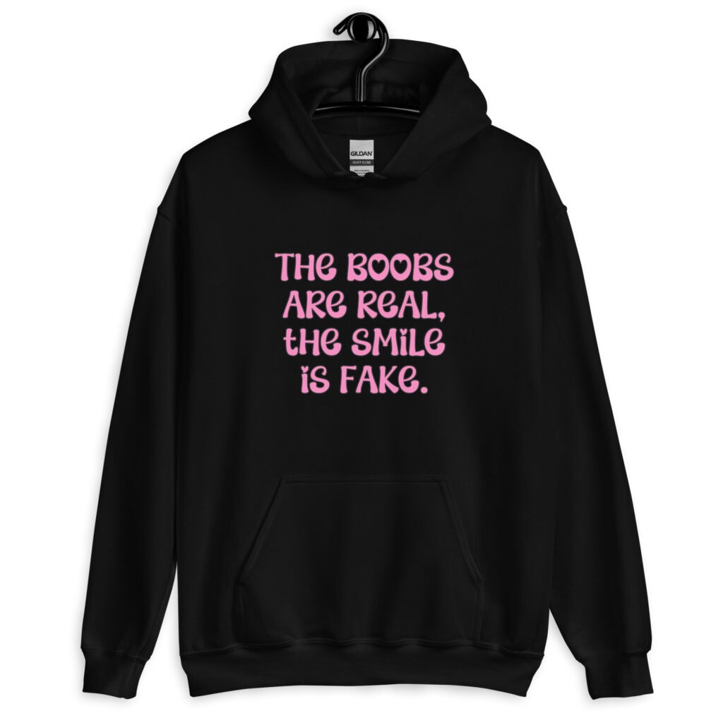 Black hoodie sweatshirt with the text 'The boobs are real, the smile is fake.' printed in pink on the front.