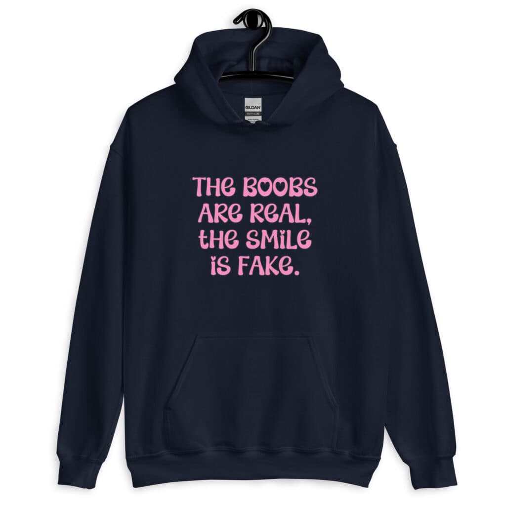Navy blue hoodie sweatshirt with the text 'The boobs are real, the smile is fake.' printed in pink on the front.