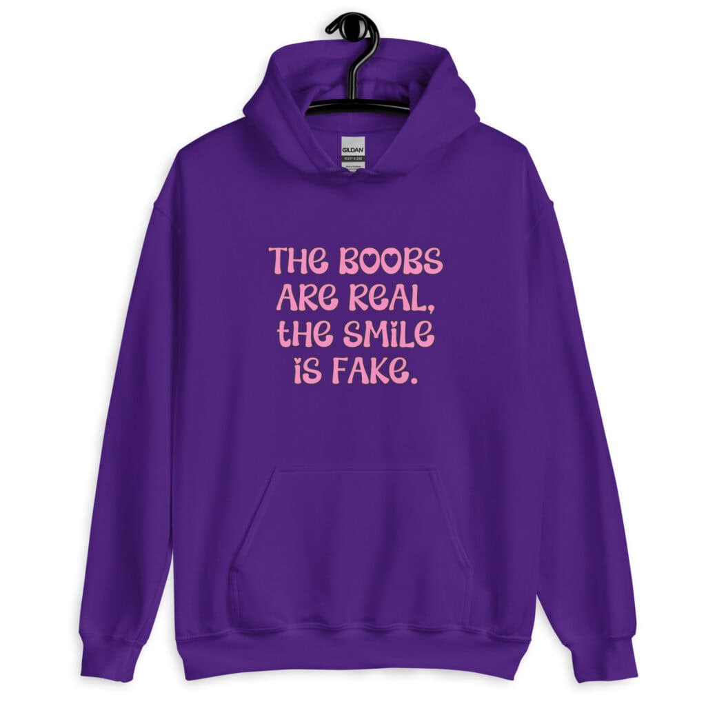 Purple hoodie sweatshirt with the text 'The boobs are real, the smile is fake.' printed in pink on the front.