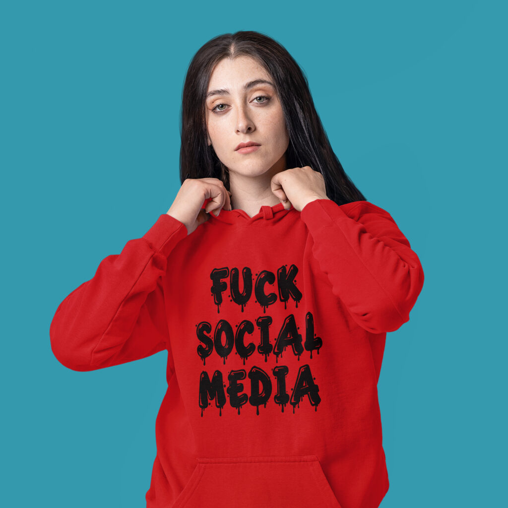 Woman wearing a red hoodie sweatshirt with the text 'Fuck social media' printed on the front in drippy graffiti style font.