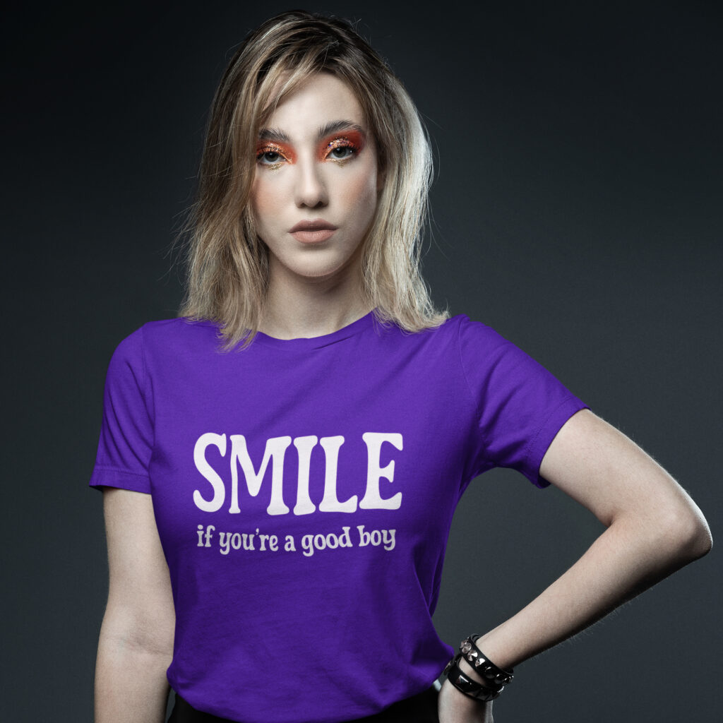 Woman wearing a purple t-shirt with the text 'SMILE if you're a good boy' printed on the front.