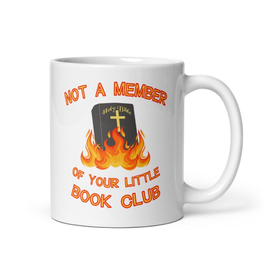 White ceramic mug with image of a burning bible and the text 'Not a member of your little book club' printed on both sides.