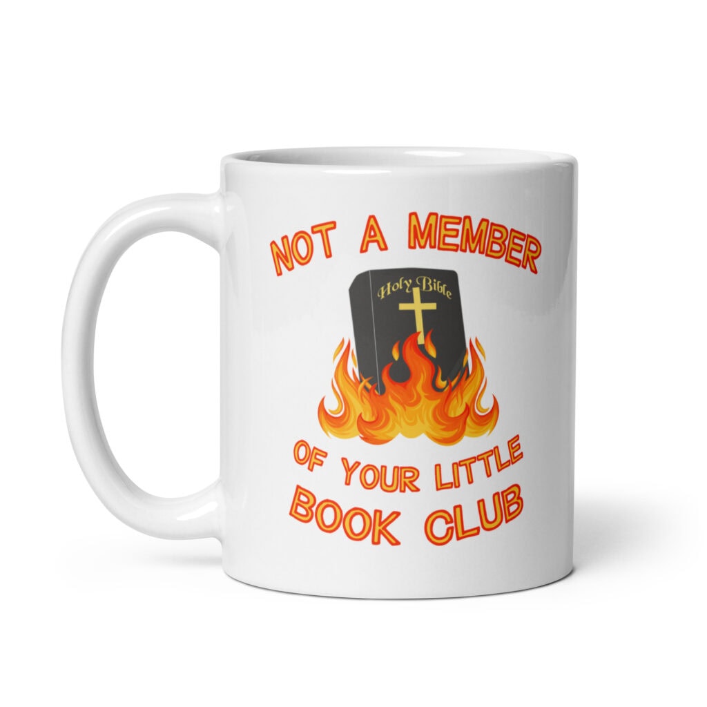 White ceramic mug with image of a burning bible and the text 'Not a member of your little book club' printed on both sides.