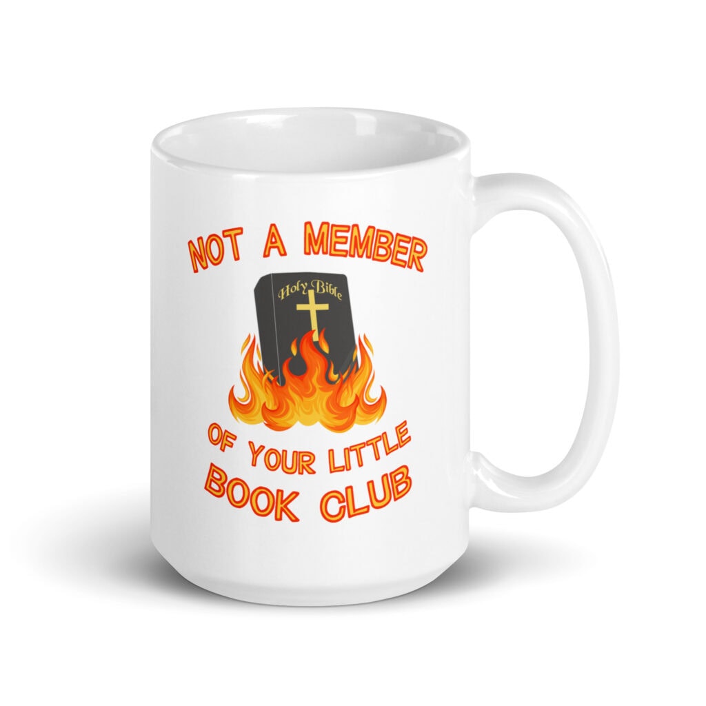 White ceramic mug with image of a burning bible and the text 'Not a member of your little book club' printed on both sides.