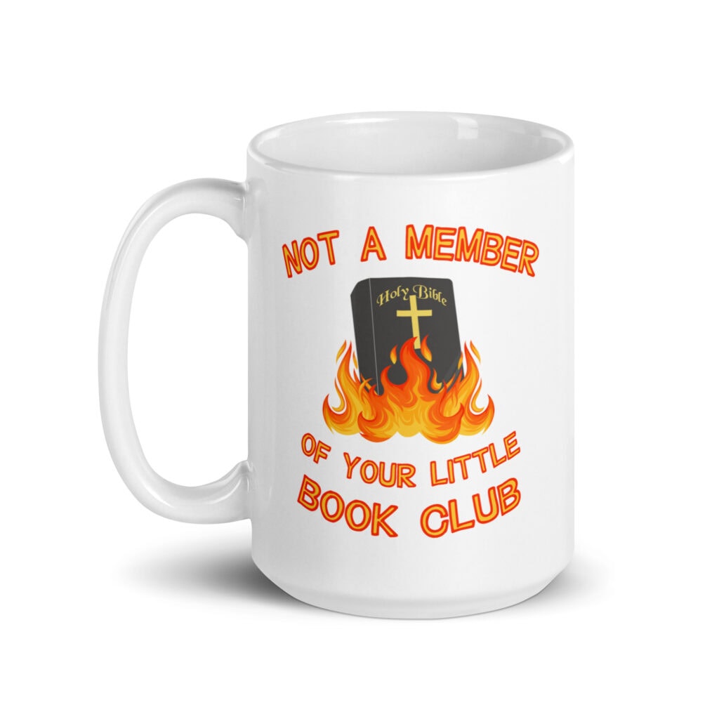 White ceramic mug with image of a burning bible and the text 'Not a member of your little book club' printed on both sides.