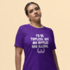 Woman wearing a purple t-shirt with the text 'I'd be topless, but my nipples are illegal' printed on the front. There is a ling drawing of breasts under the text.