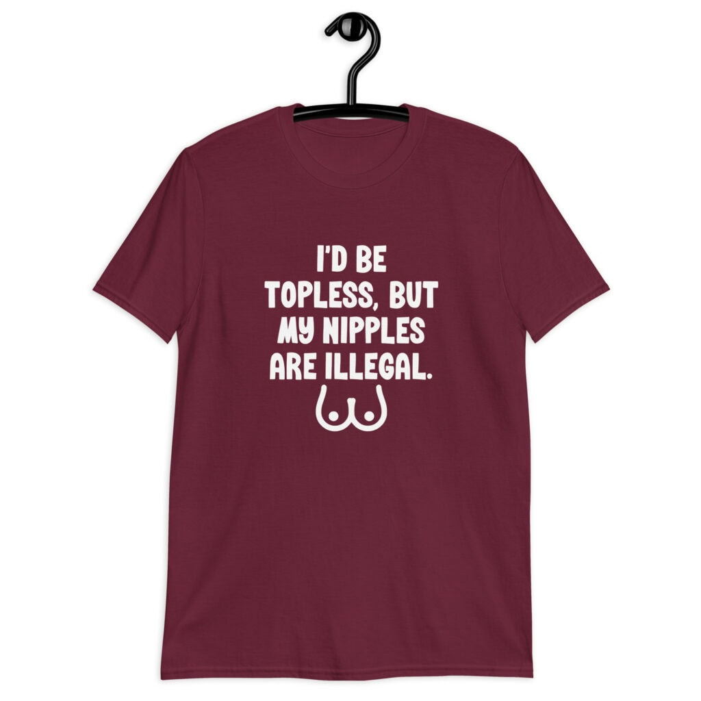 Maroon t-shirt with the text 'I'd be topless, but my nipples are illegal' printed on the front. There is a ling drawing of breasts under the text.