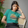 Woman wearing a jade color t-shirt with a retro sunrise design and the text 'Please don't talk to me' printed on the front.