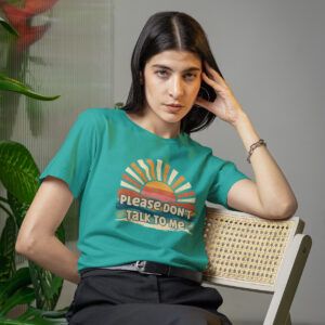 Woman wearing a jade color t-shirt with a retro sunrise design and the text 'Please don't talk to me' printed on the front.