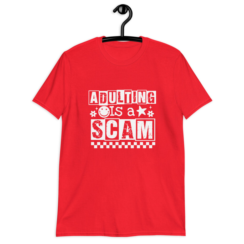 Red t-shirt with bold white text reading ‘Adulting is a Scam’ in mixed block and distressed fonts. The design includes a smiley face, star, and flower icons, with a checkerboard stripe along the bottom.