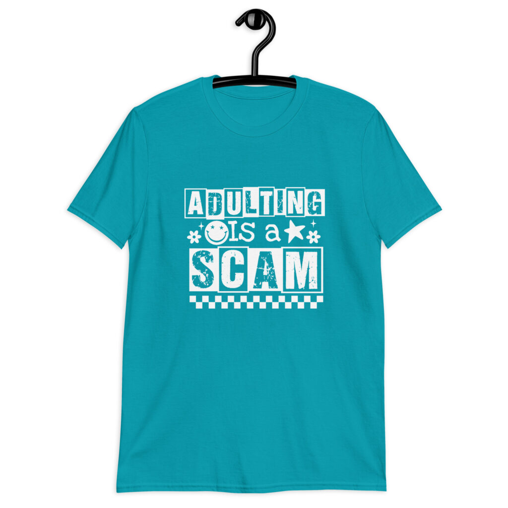 Tropical blue t-shirt with bold white text reading ‘Adulting is a Scam’ in mixed block and distressed fonts. The design includes a smiley face, star, and flower icons, with a checkerboard stripe along the bottom.