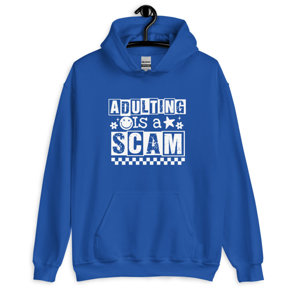 Royal blue hoodie sweatshirt with bold white text reading ‘Adulting is a Scam’ in mixed block and distressed fonts. The design includes a smiley face, star, and flower icons, with a checkerboard stripe along the bottom.