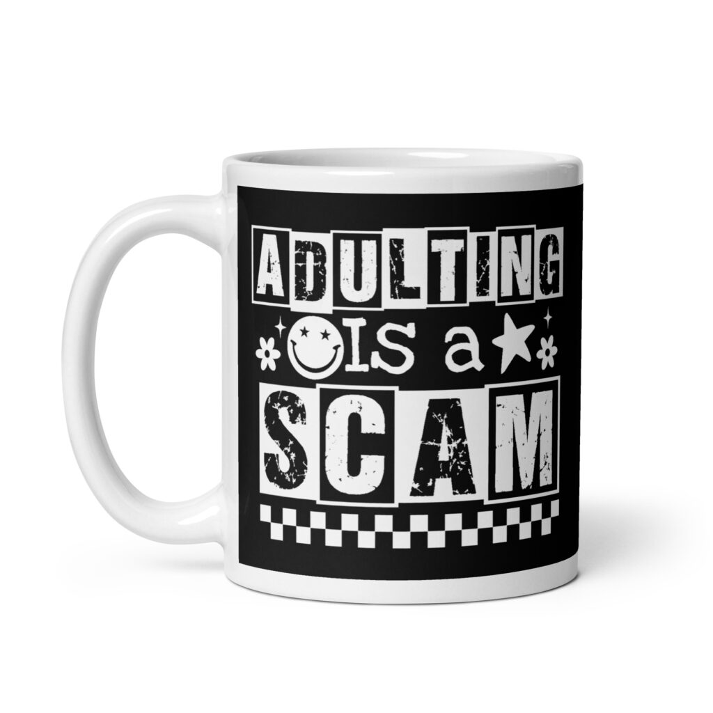 White ceramic mug featuring a black wraparound design with bold distressed white text reading ‘Adulting is a Scam.’ The text includes a smiley face, star, and flower icons, with a white checkerboard stripe along the bottom.