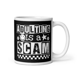 White ceramic mug featuring a black wraparound design with bold distressed white text reading ‘Adulting is a Scam.’ The text includes a smiley face, star, and flower icons, with a white checkerboard stripe along the bottom.