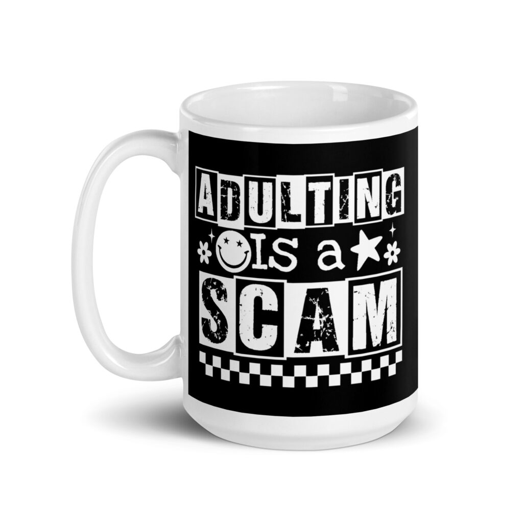 White ceramic mug featuring a black wraparound design with bold distressed white text reading ‘Adulting is a Scam.’ The text includes a smiley face, star, and flower icons, with a white checkerboard stripe along the bottom.